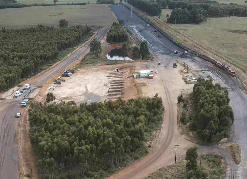 Aerial view of a rail siding, with a train on the line beside the loading area and stockpiles